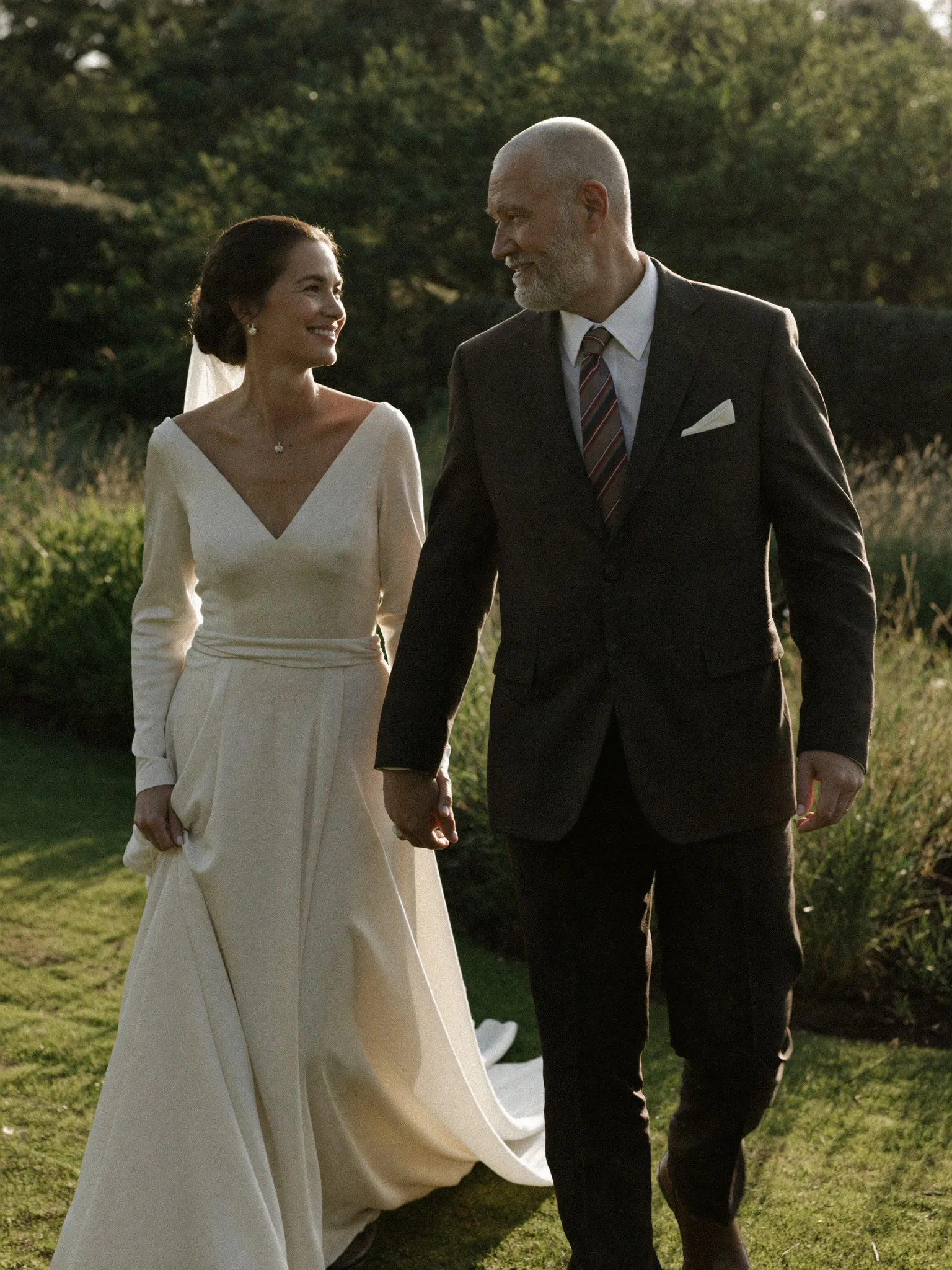Couple walking hand in hand at golden hour, editorial wedding portrait