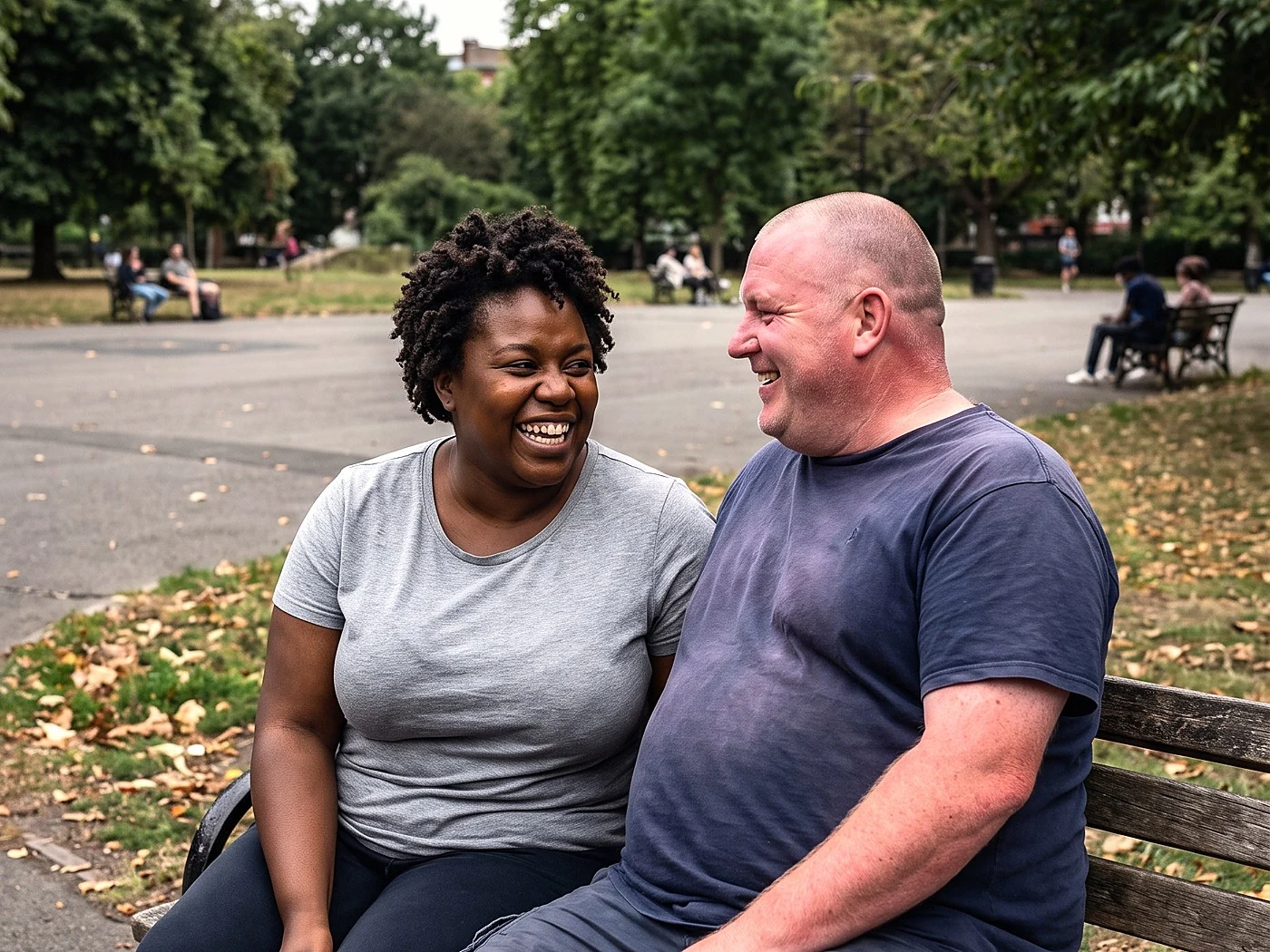 A plus-size couple laughing together on a park bench during their engagement session.